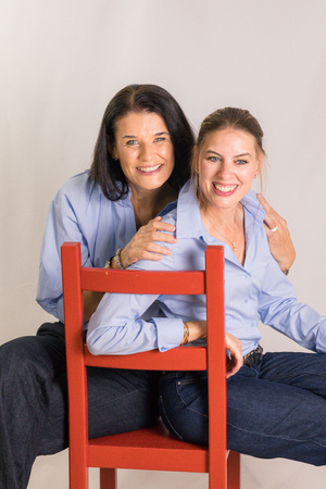 Sabine Fagitsch-Unger und Kathrin Sandtner-Friess sitzen gemeinsam auf einem roten Sessel.
