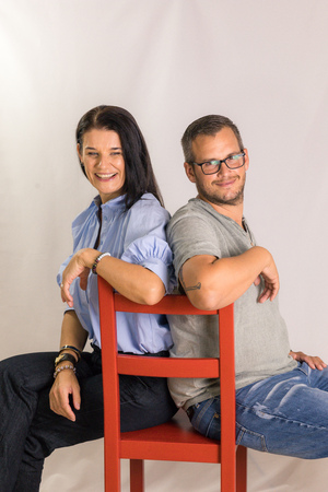 Sabine Fagitsch-Unger und Gerald Lenzenwenger sitzen Rücken an Rücken auf einem roten Sessel.